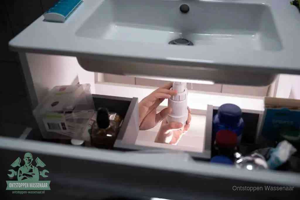 Een pompfles met zeep boven een wastafel, de heet water en afwasmiddel-methode om een vetprop in de afvoer los te maken in Wassenaar