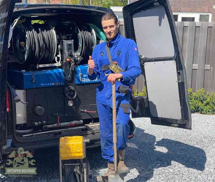 Een monteur bij de werkbus met grote hogedruk-slanghaspels, apparatuur voor hardnekkige afvoerverstoppingen in Wassenaar