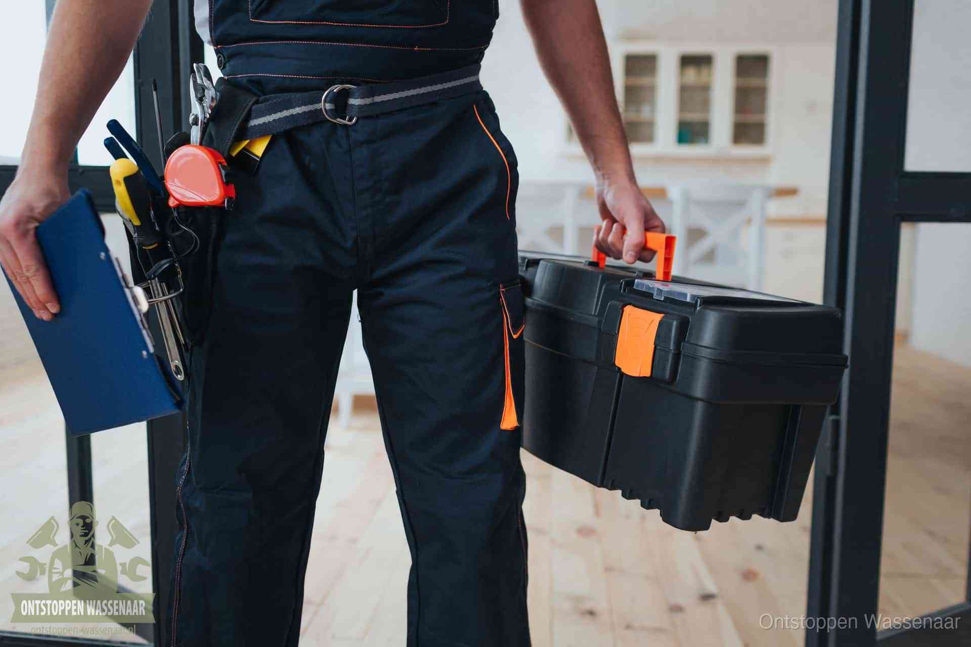 Een monteur met gereedschapsriem en klembord in een keuken, klaar om een transparante prijs voor het gootsteen ontstoppen in Wassenaar te geven