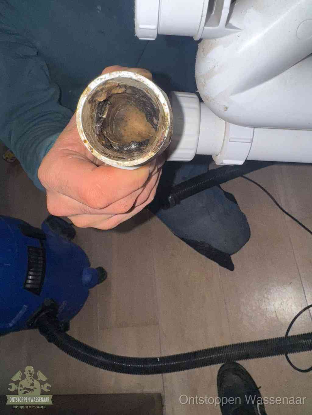 Een losgekoppelde afvoerbuis die van binnen volledig is dichtgeslibd met vet en aanslag, de meest voorkomende oorzaak van een verstopte gootsteen in Wassenaar