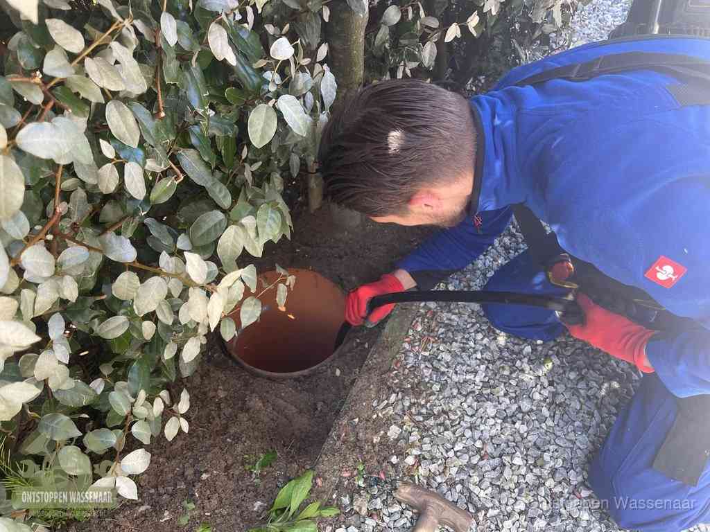 Monteur reinigt een rioolput met een slang, periodieke rioolreiniging in Wassenaar