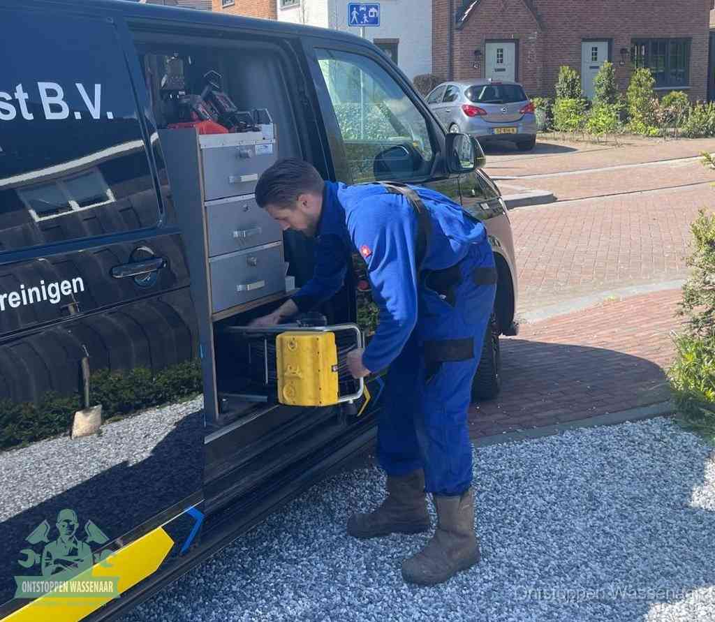 Een monteur pakt buiten op de oprit gereedschap uit de bedrijfsbus, het moment om een professional in te schakelen voor een verstopte afvoer in Wassenaar