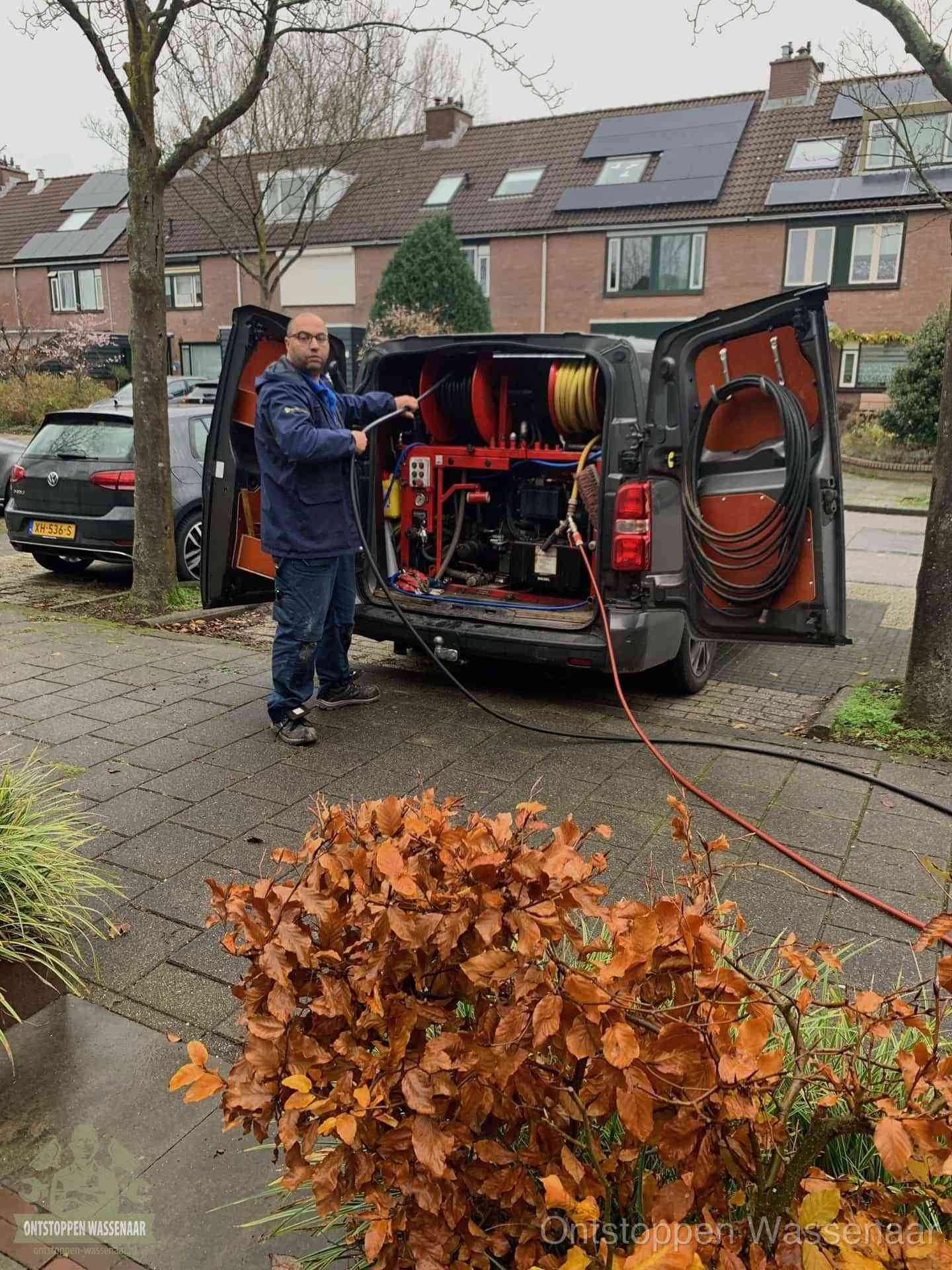 Monteur met rioolreinigingsbus levert rioolservice in de wijk in Wassenaar