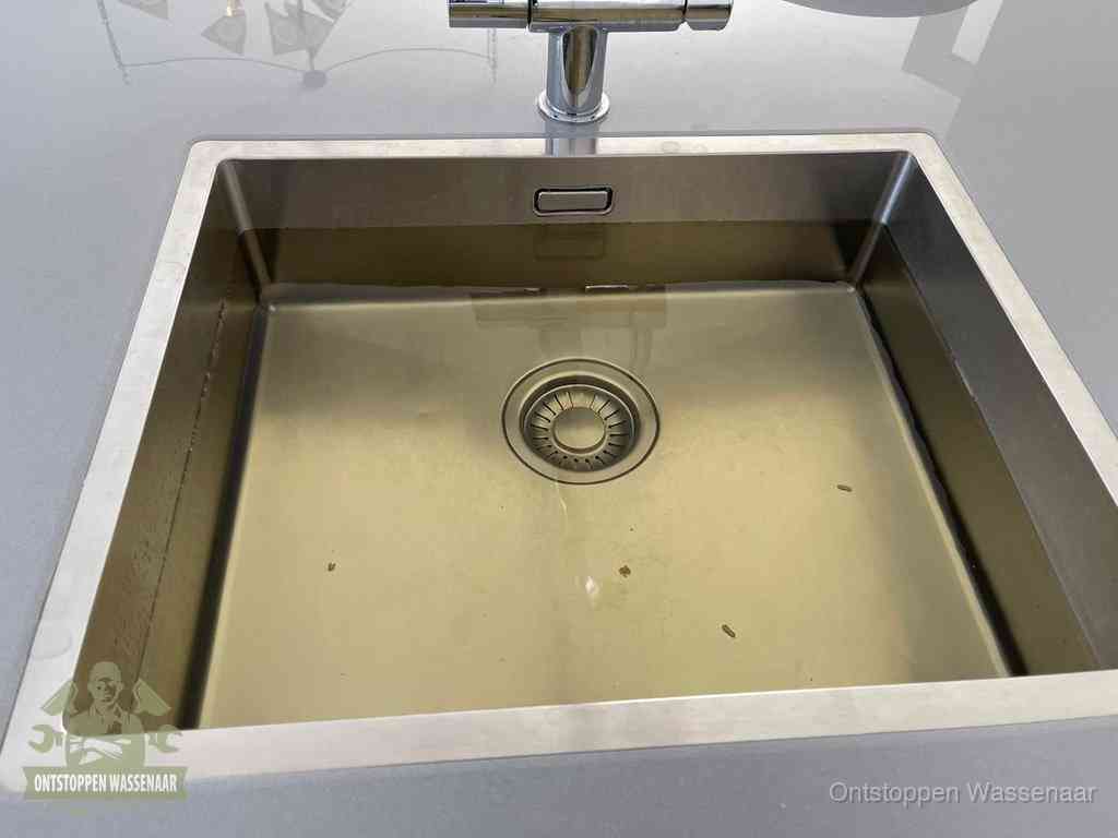 Stilstaand water in een rvs spoelbak dat niet wegloopt, een duidelijk signaal van een gootsteenverstopping in Wassenaar