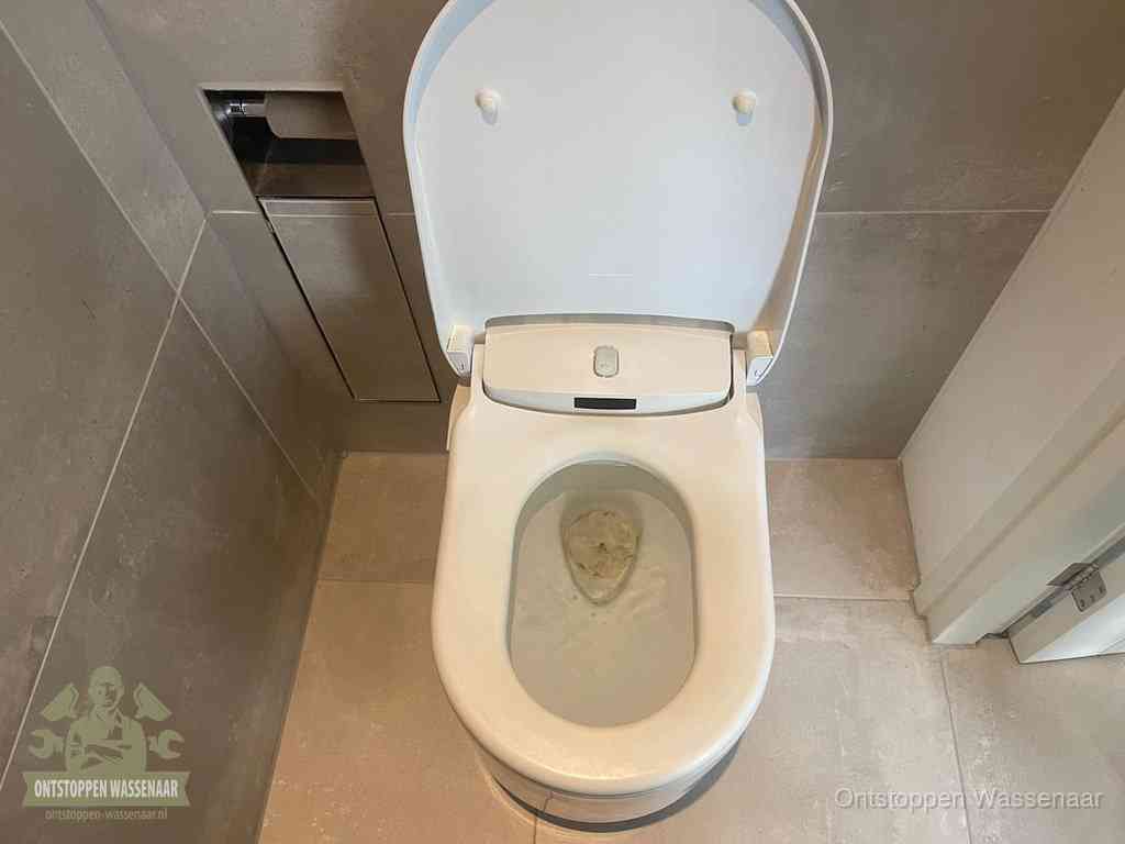Een wit hangtoilet waarin een prop wc-papier op het water blijft drijven, een duidelijk signaal van een verstopte wc in Wassenaar