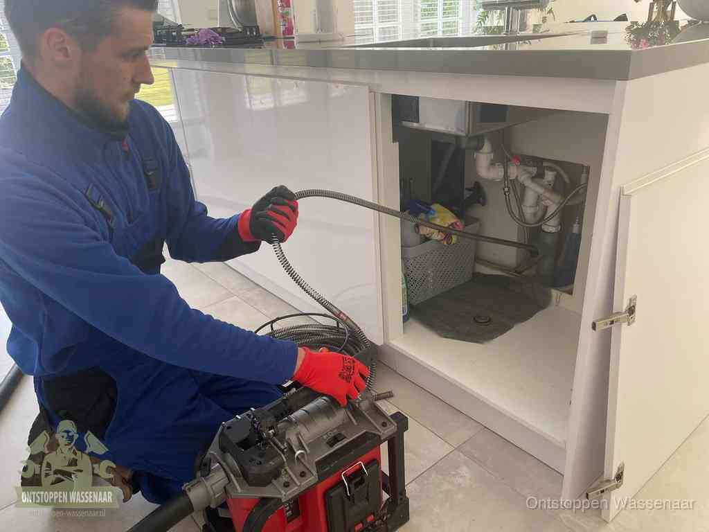 Een monteur reinigt de keukenafvoer grondig met een veermachine om terugkerende gootsteenverstoppingen te voorkomen in Wassenaar