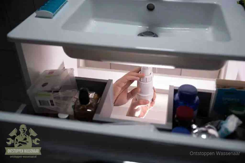 Een pompfles met zeep boven een wastafel in de toiletruimte, de warm water en afwasmiddel-methode om de wc te ontstoppen in Wassenaar